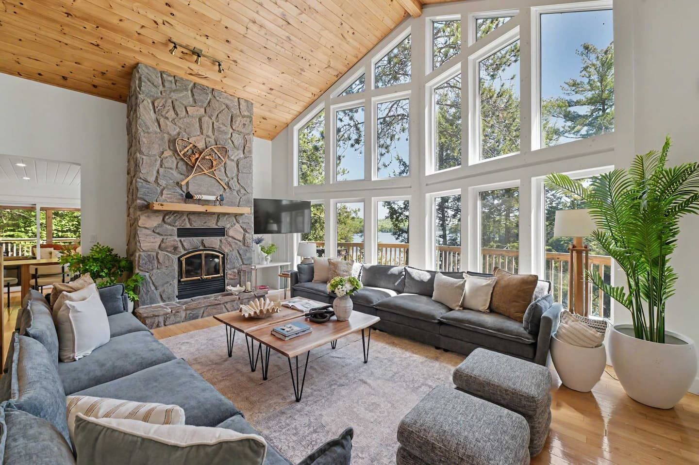 The great room with a stone fireplace and floor-to-ceiling lake-facing windows